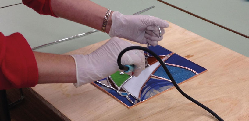 Soldering a stained glass panel in the studio
